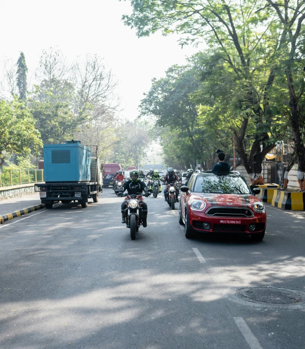 two motorcycles drive in opposite directions, as a car pulls up along the road