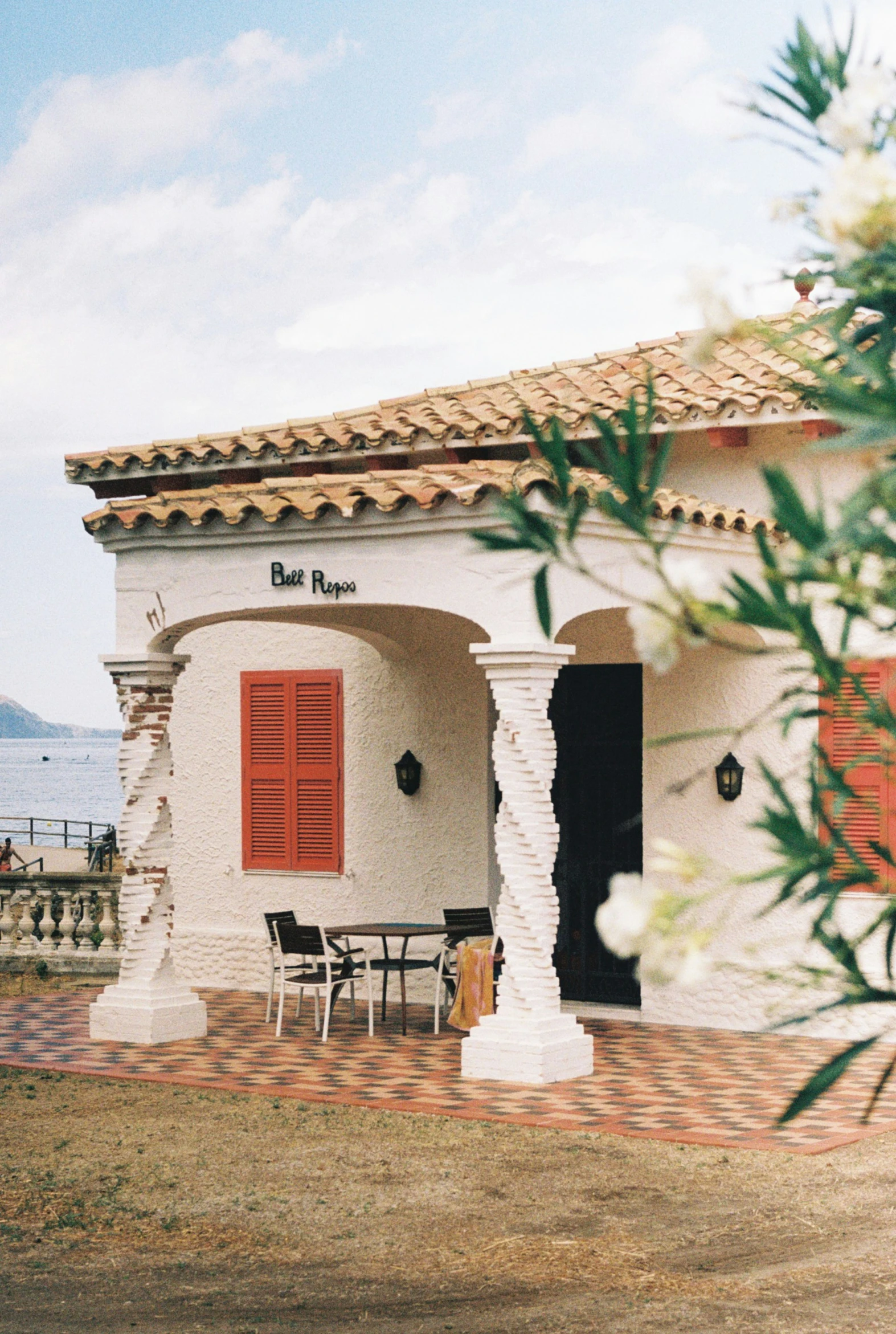 a white house with red shutters and table set outside