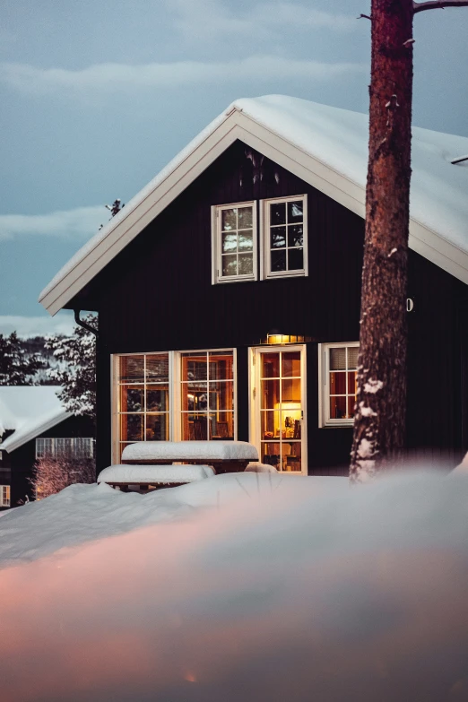 a black cabin is snowed up in the dark