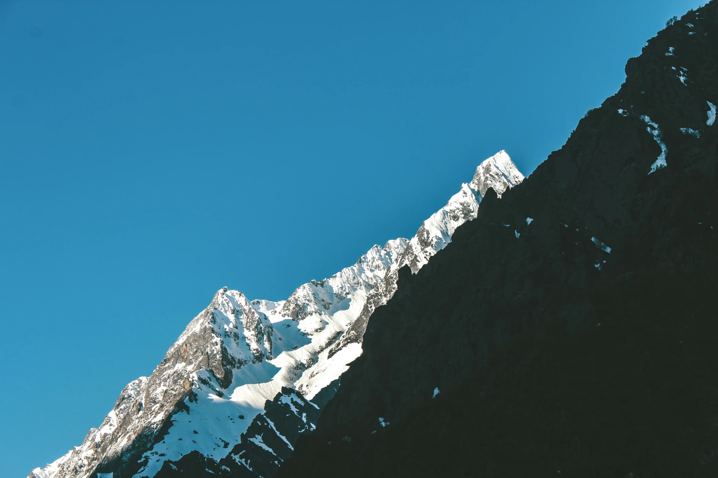 the top of a snowy mountain is shown with the blue sky above it