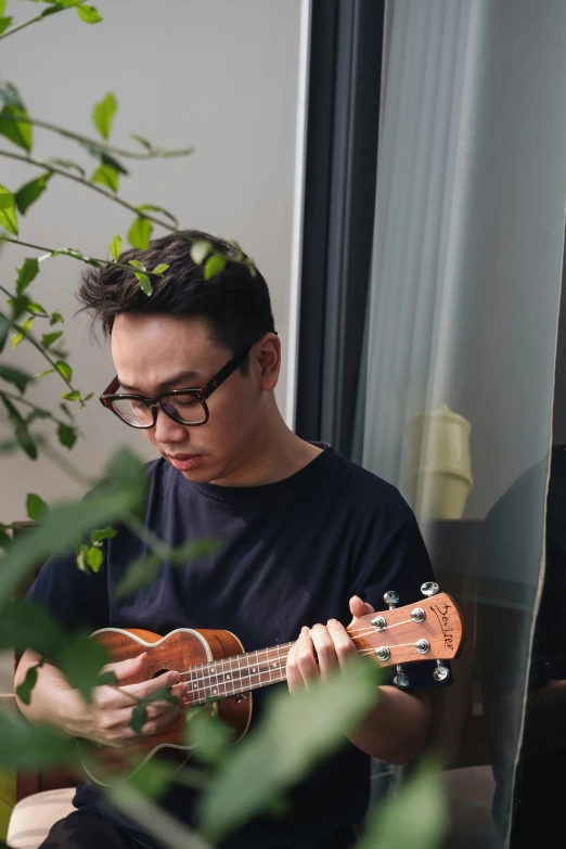 a young man wearing glasses playing an ukelele