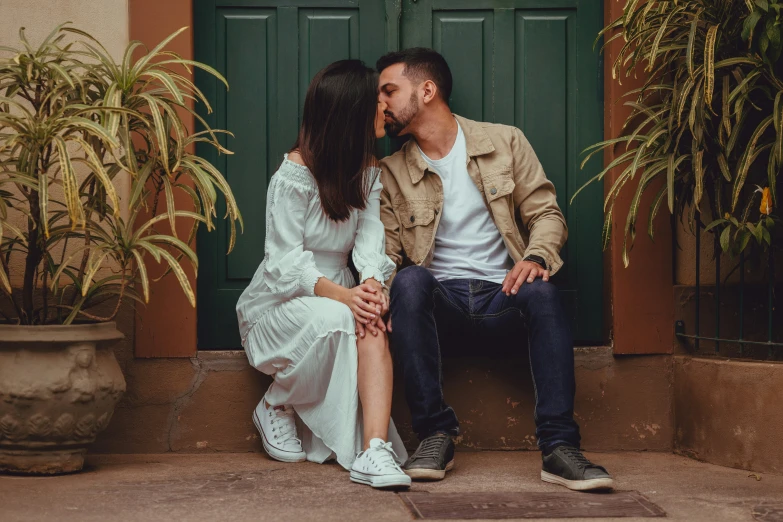 a young couple cuddling in front of a doorway as they kiss