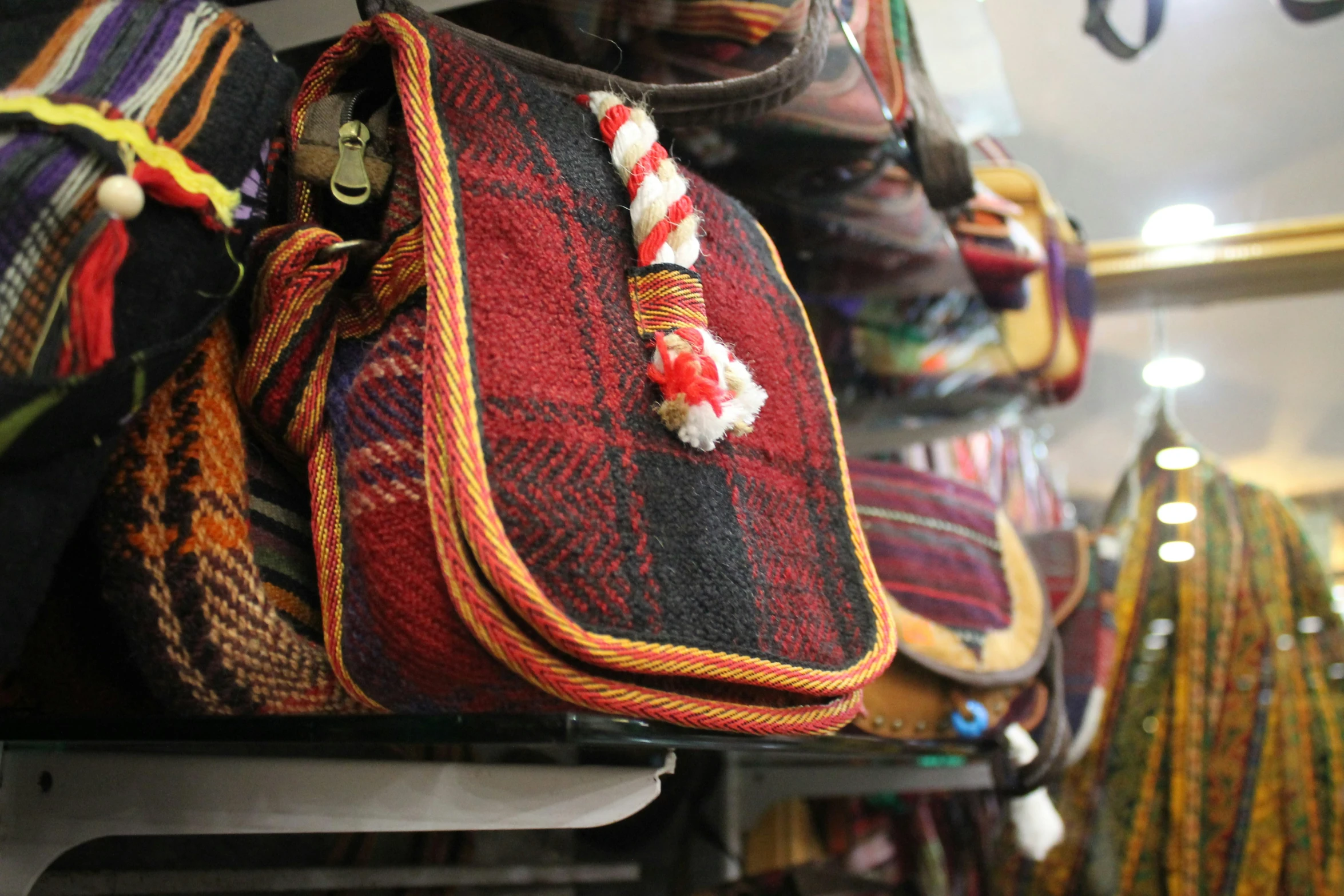 multi colored cloth purses are stacked up and organized on a shelf