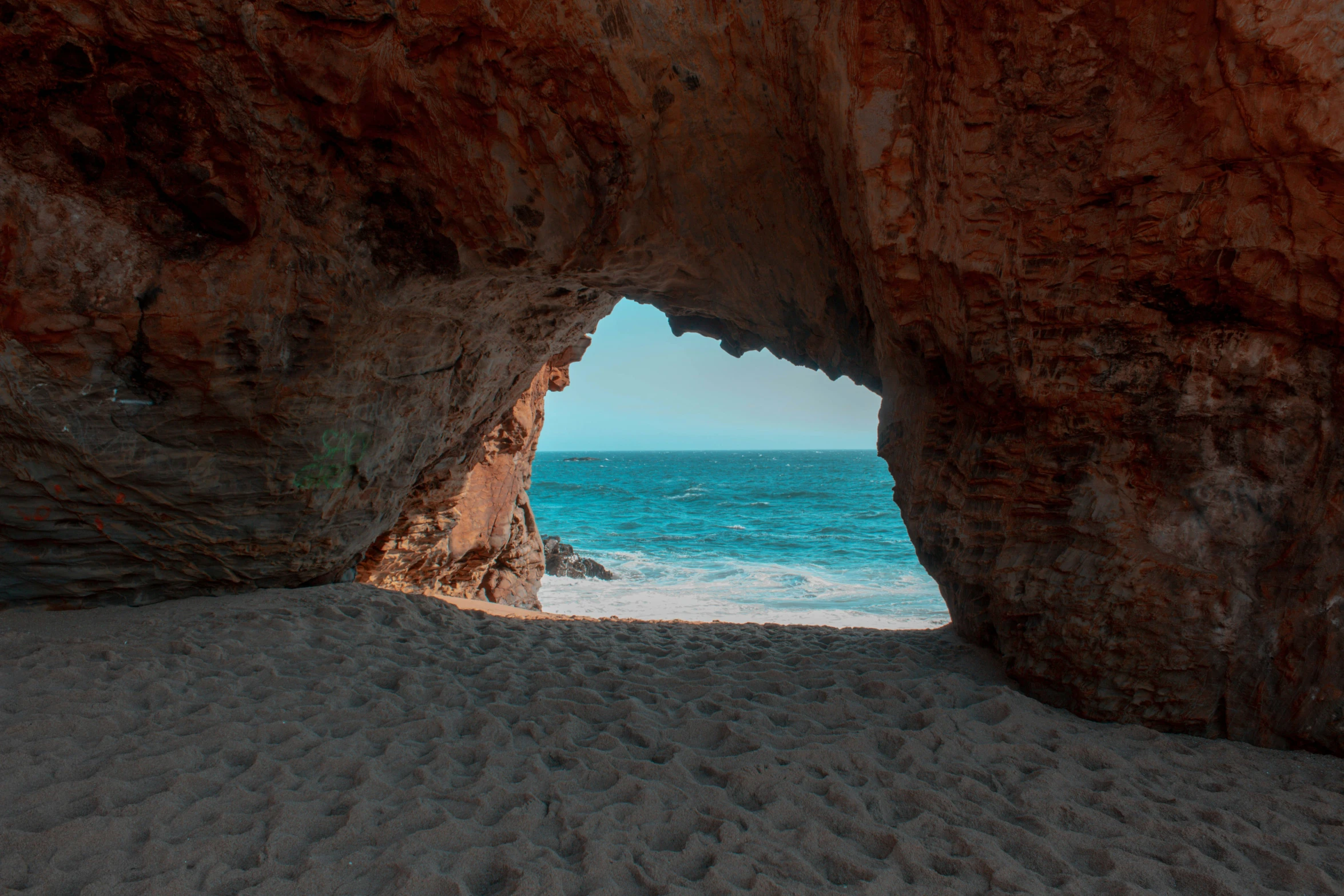 an image of a sandy beach under a very big rock