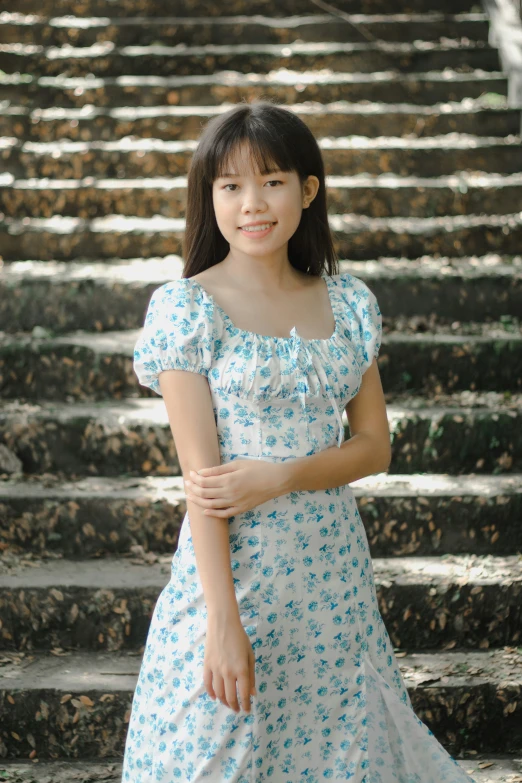 a girl poses on a stair case, looking at the camera