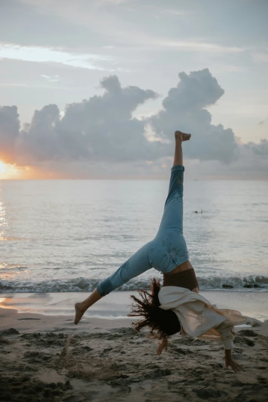 a girl performs a handstand on the beach