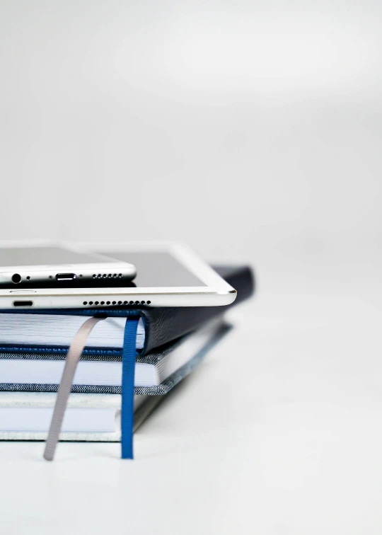 a stack of binders that has a laptop and an ipad on it