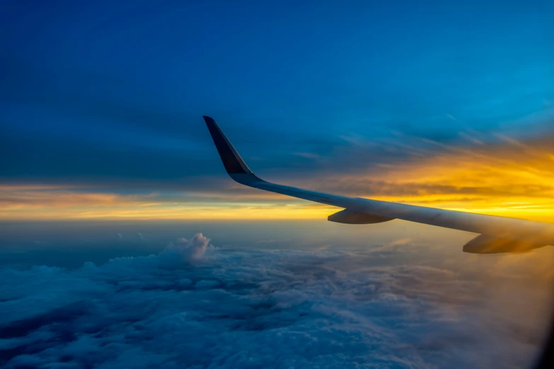 an airplane wing, with the sun low on top of it