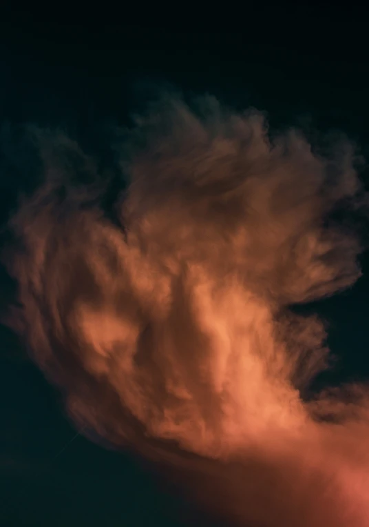 a large cloud looms over a city at night