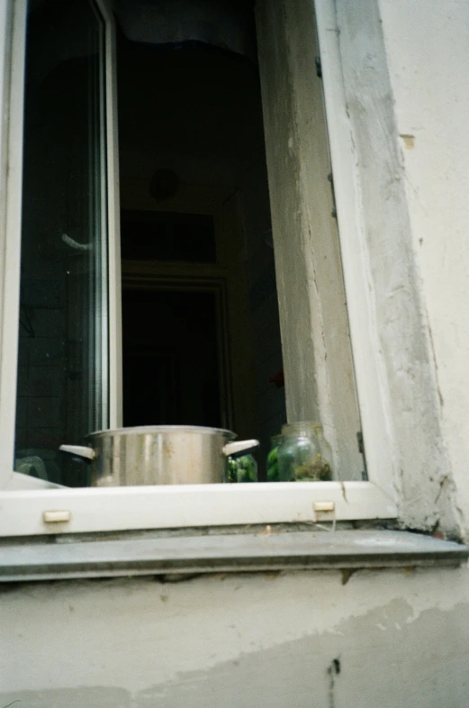 an open window in front of a pot and pan on the window sill