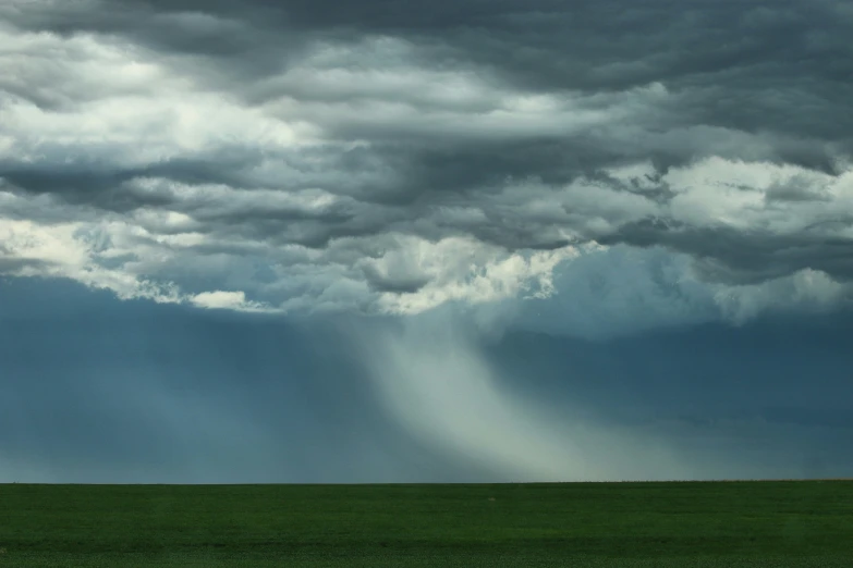 a lone horse grazing in an open field beneath stormy skies