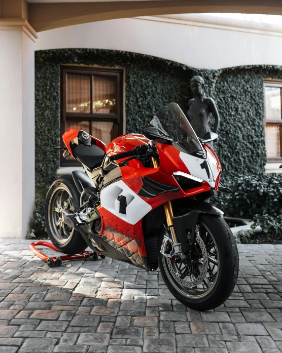 red motorcycle parked on a brick patio with green wall behind it