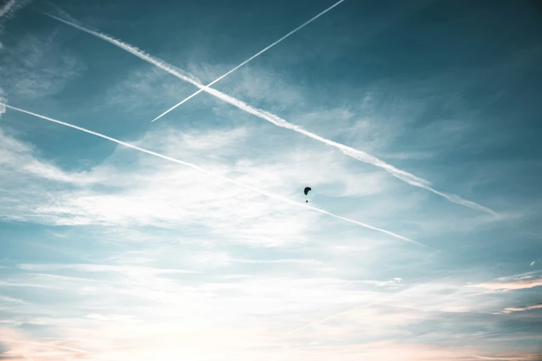 kites fly through the sky with contrails