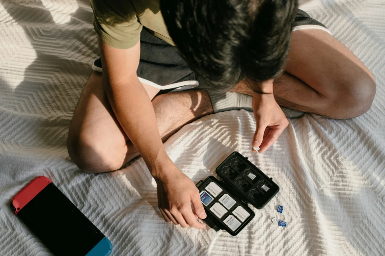 a boy on the bed holding onto two electronic devices