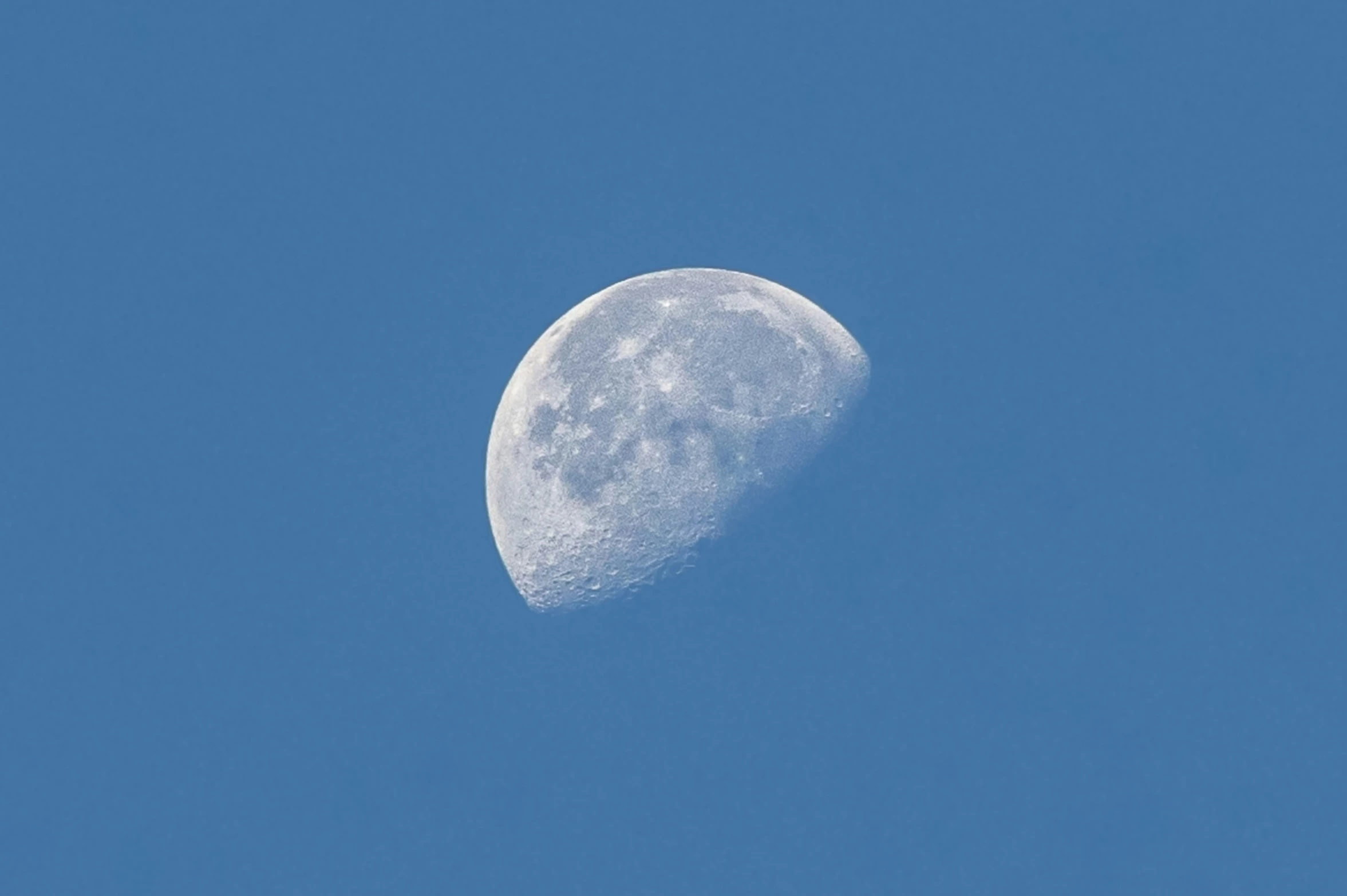 the moon in a clear blue sky with a cloudy background