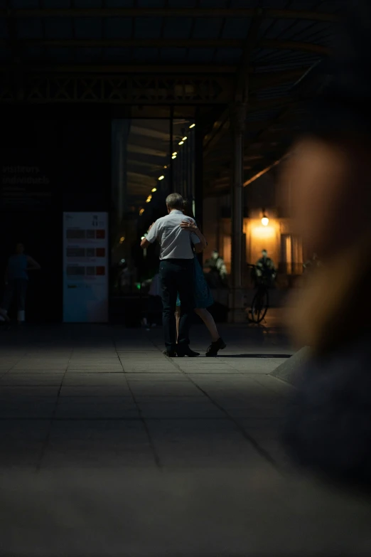 two people standing under an open walkway at night