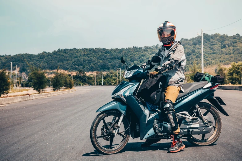 a man sitting on a motorcycle near some trees