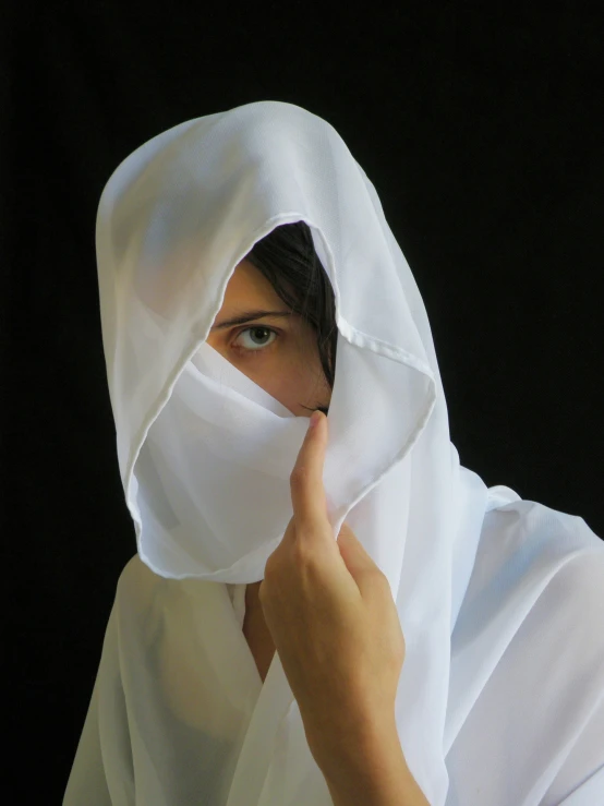 a woman wearing a white shawl covering her face