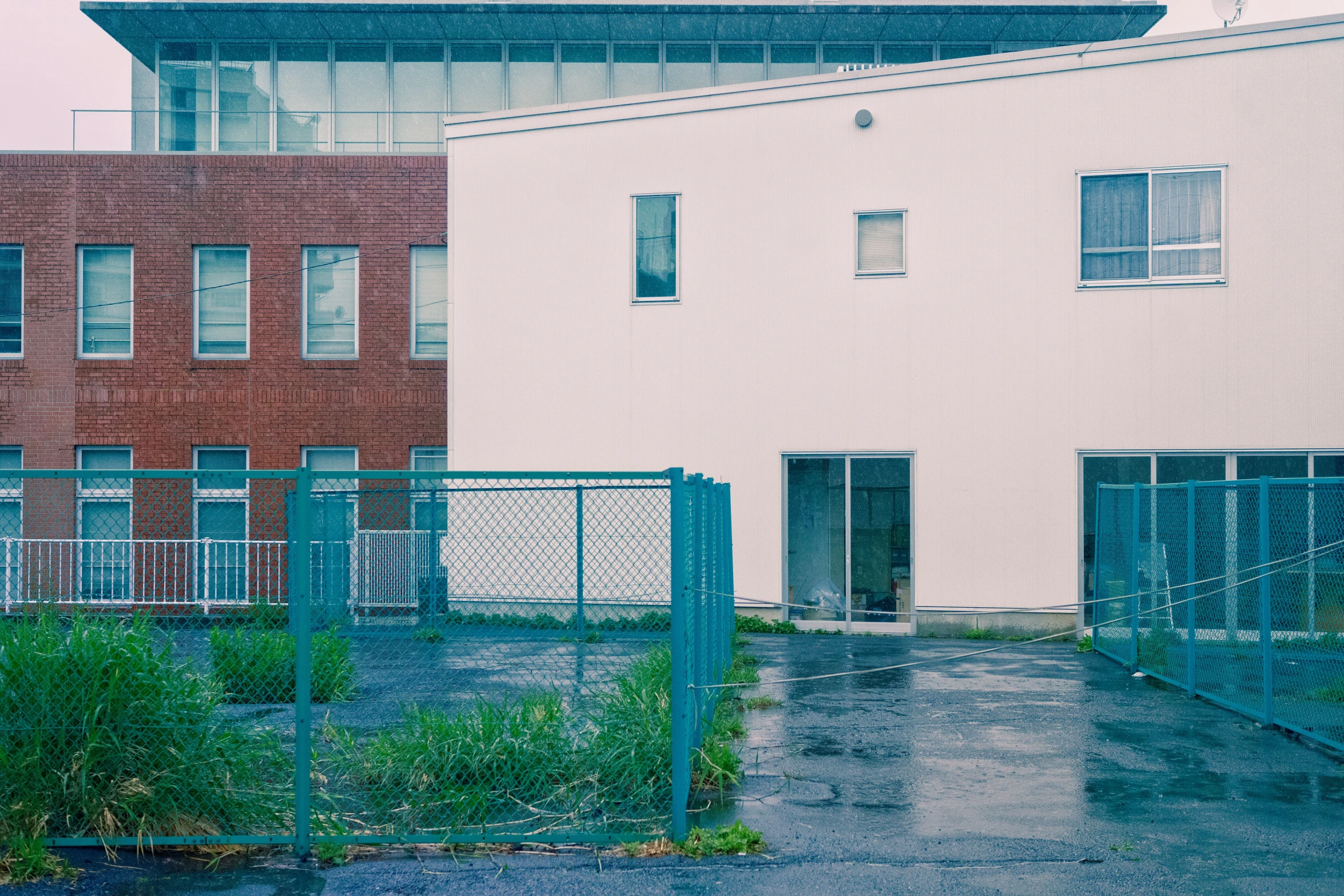 an empty building with green iron fences and bushes near by