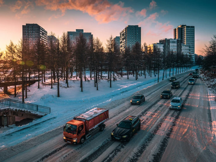 a truck traveling down a snowy road surrounded by tall buildings