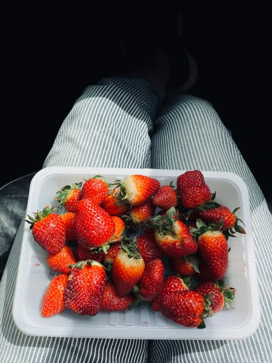 a white tray filled with fresh strawberries on top of a bed