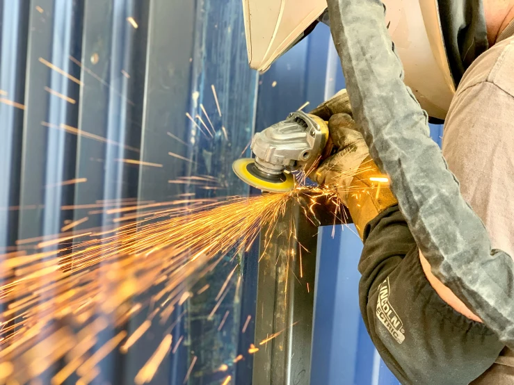 a man grinds metal on a driller