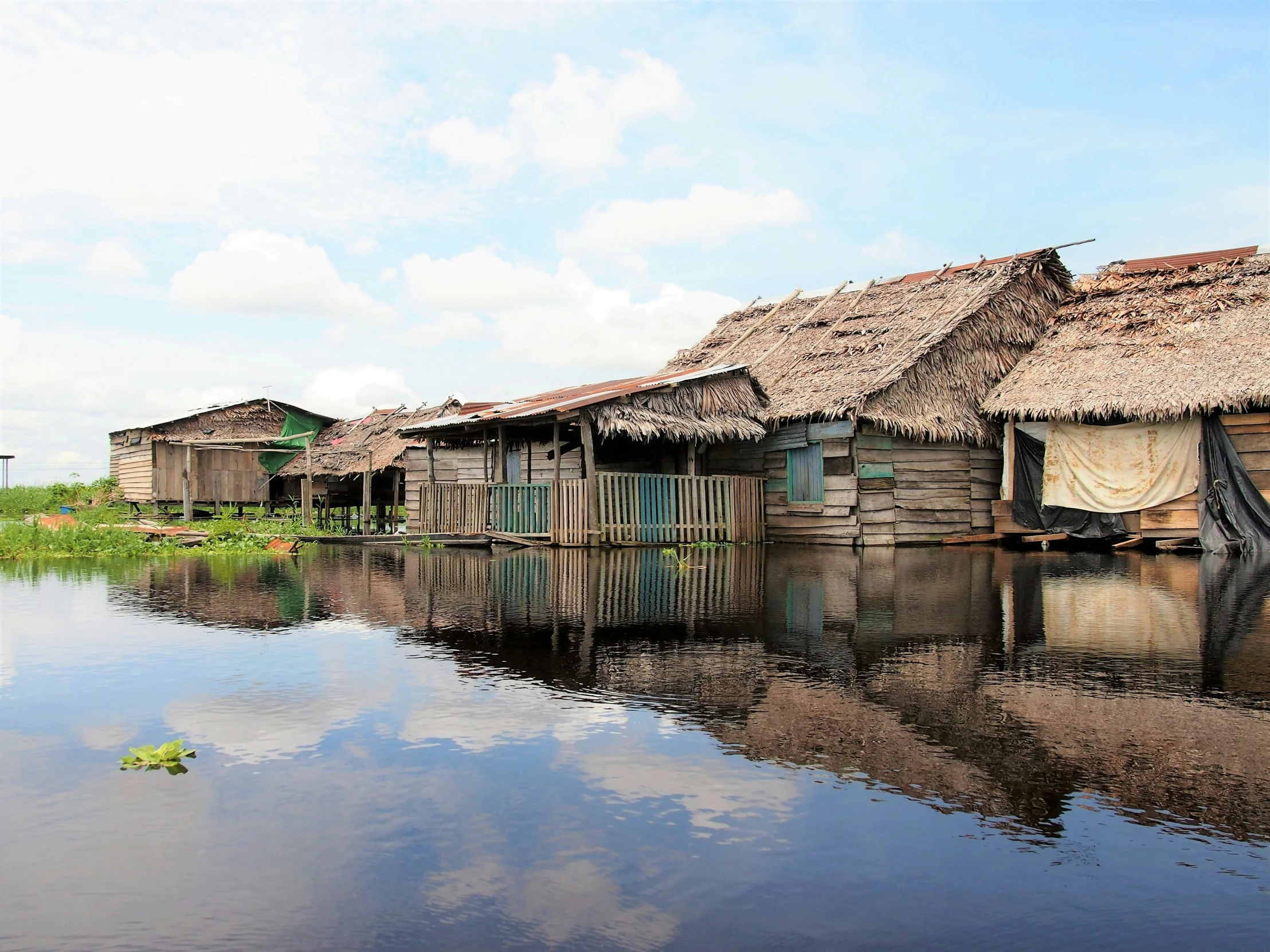 a bunch of houses sitting in the water near some grass