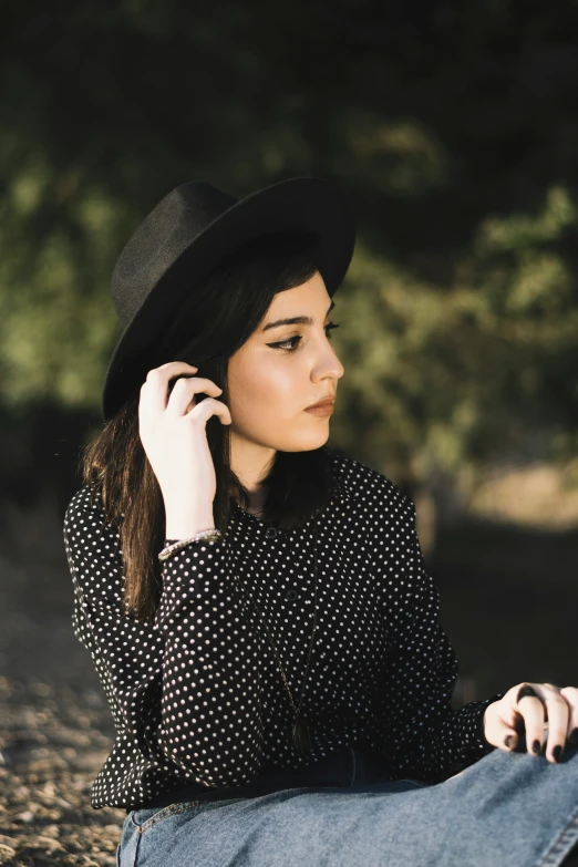 a woman wearing a hat, black shirt and jeans talking on her cell phone