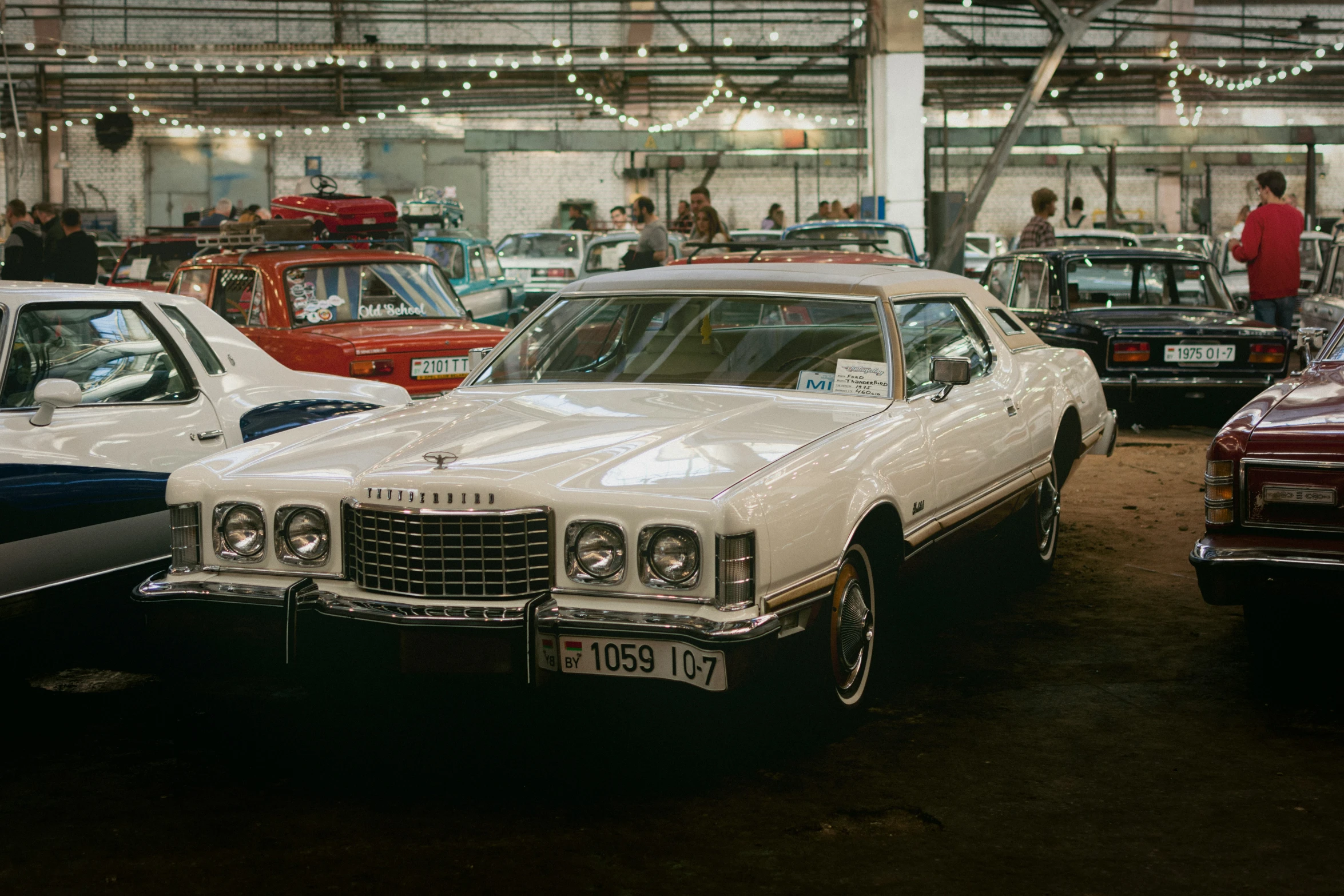 white vintage cars parked inside of a garage