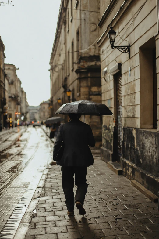 a man in a suit carrying an umbrella down a street