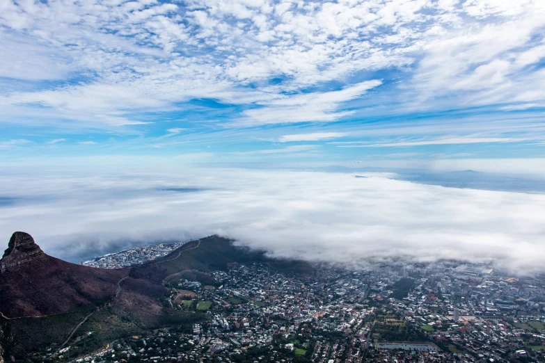 clouds hovers over a city and mountain under blue sky