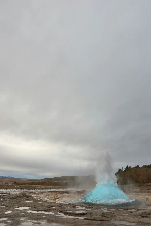 a steaming pipe surrounded by water with clouds in the background