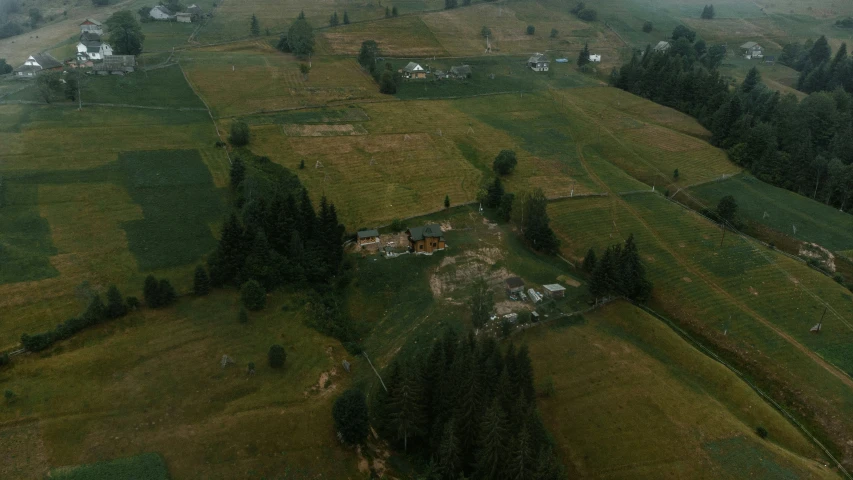 a big grassy hill with some trees and buildings