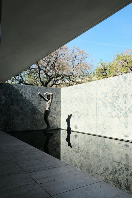 a sculpture by a concrete wall outside of a building