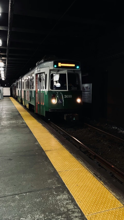 a train on the track with lights coming on at night