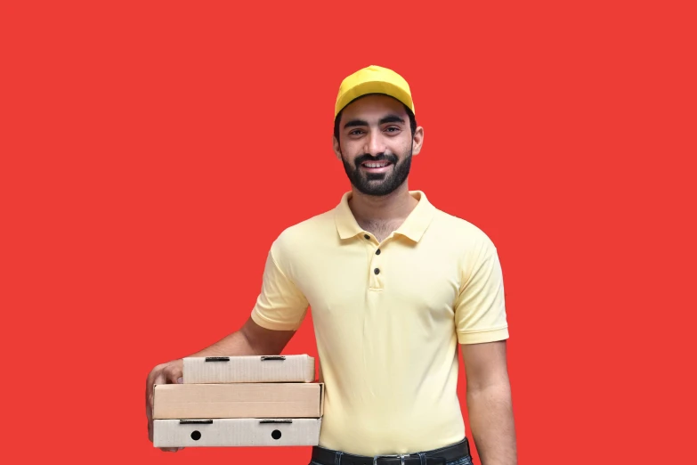 a man standing in front of a red backdrop holding a package of pizza