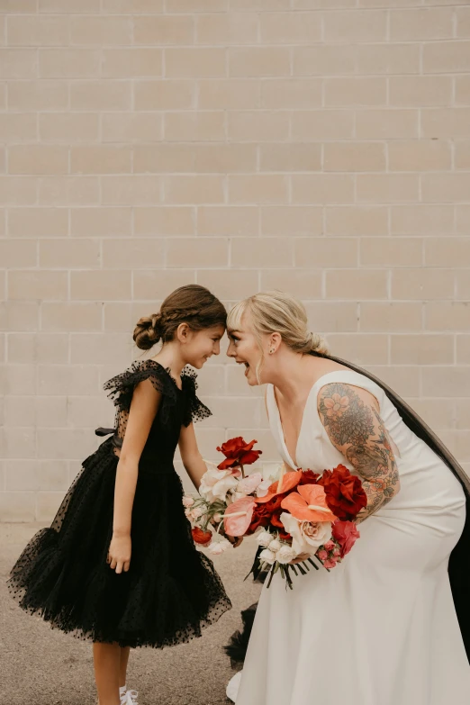 two beautiful brides, one holding a flower bouquet, in front of a brick wall