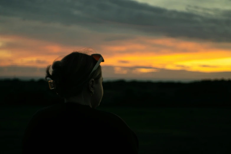 woman with eye glasses looking up at sunset