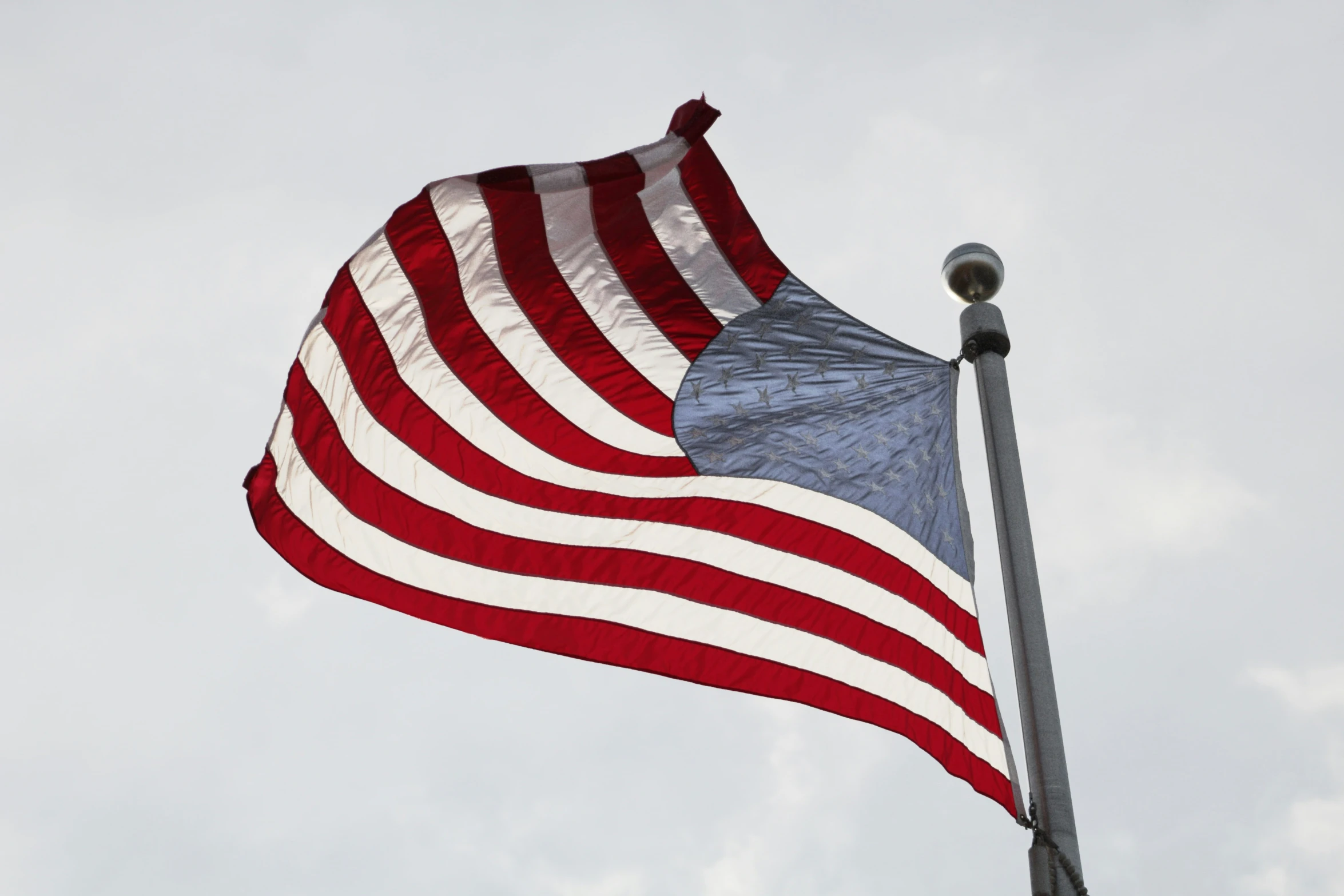 an american flag flying in the wind with cloudy sky