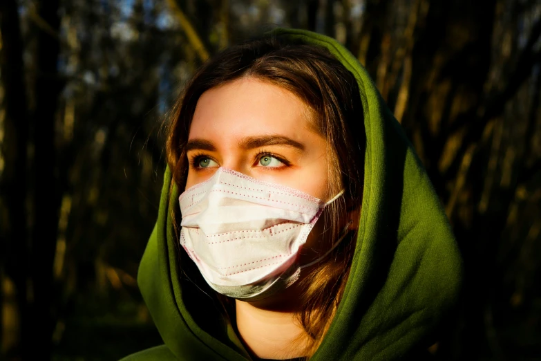 a woman in a hood and mask staring to the side