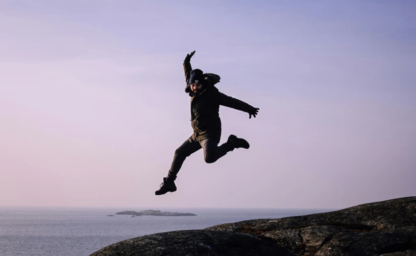 a man jumping with his arms outstretched over the ocean