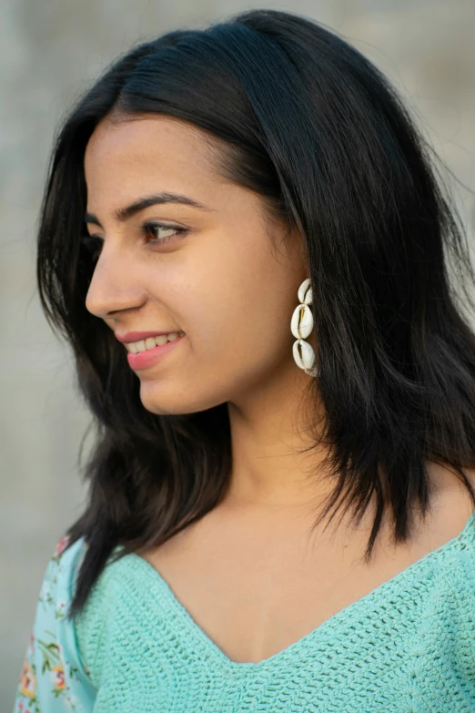 woman wearing an aqua green top and pearl earring