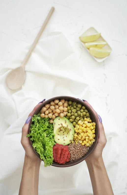 a person holding a bowl filled with some assorted vegetables