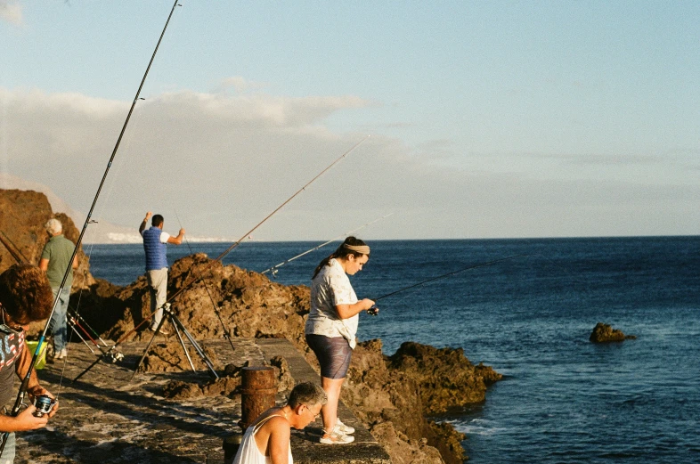 the people are all fishing from rocks by the water