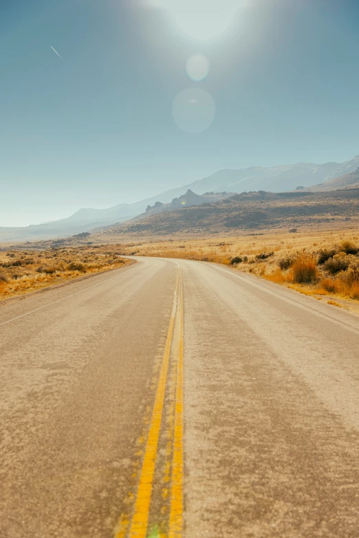 the sun is shining on a desert road