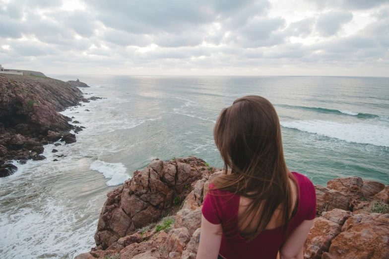 a person sitting on a cliff overlooking the ocean