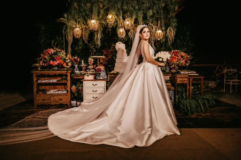 a bride is posing in a dress with flowers on the desk