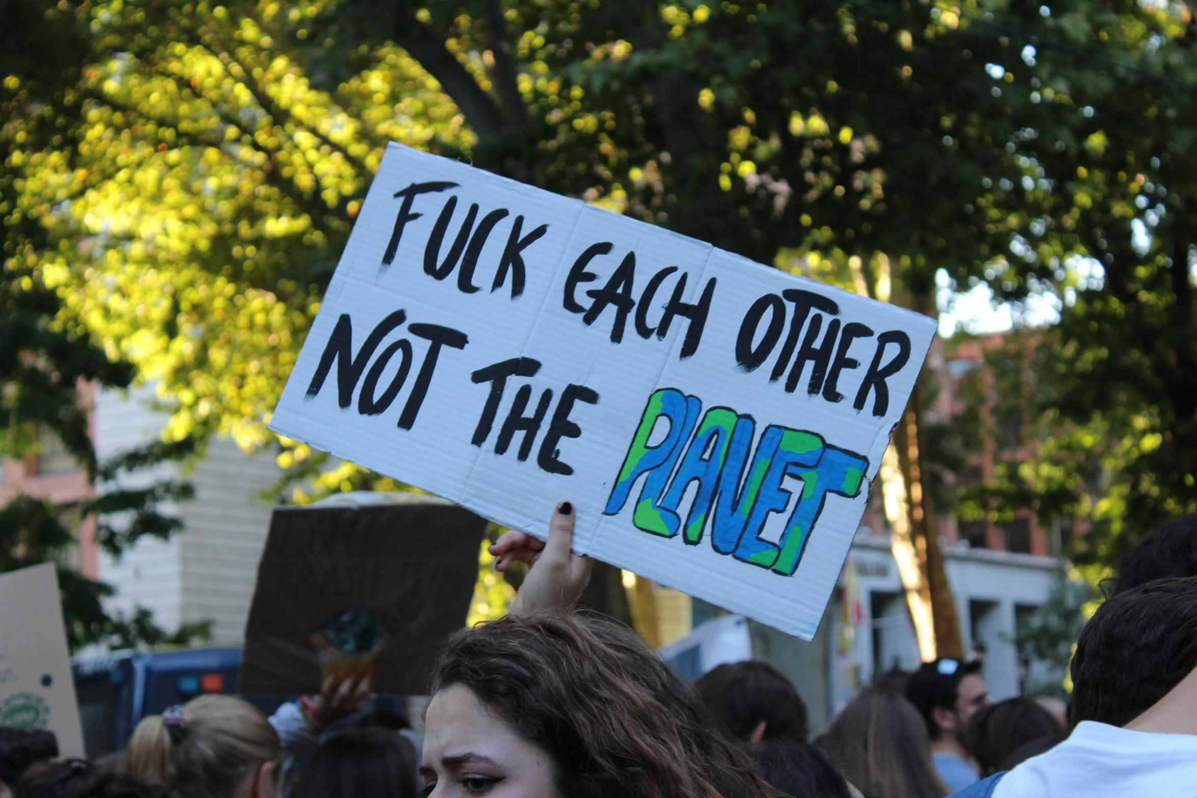 a woman holds up a sign that reads, ing gay other not the planet