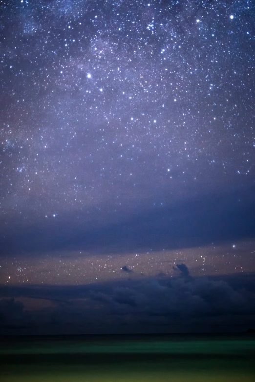 stars above the ocean and a hill in the distance