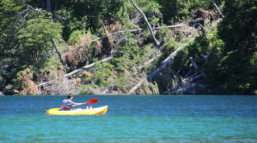 a person on a yellow kayak paddling across a lake